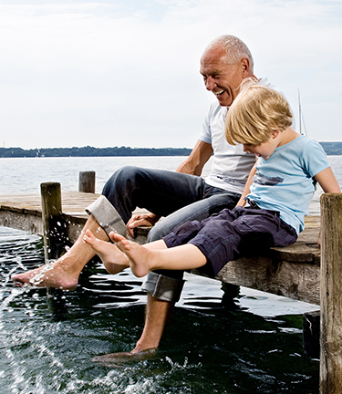 Retirement Pension Fully vested employee enjoying retirement with his grandson on a dock with their feet in the water